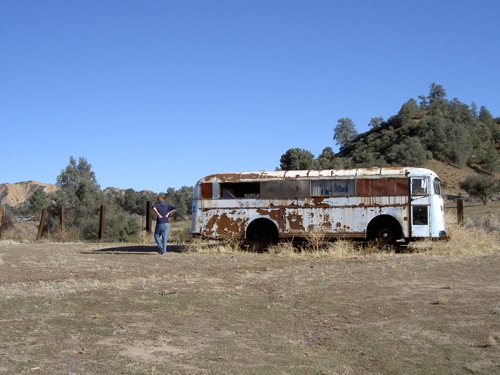 Doug looking at a rusty old bus at his uncle's ranch