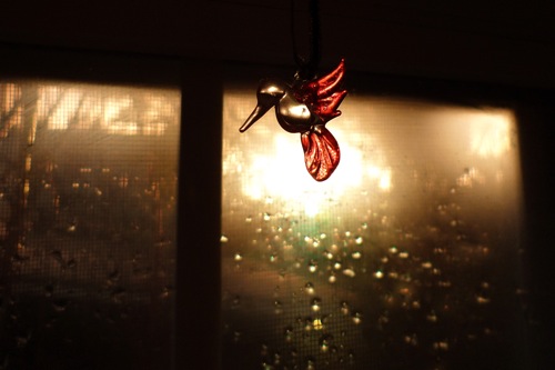 a small glass hummingbird by a window
