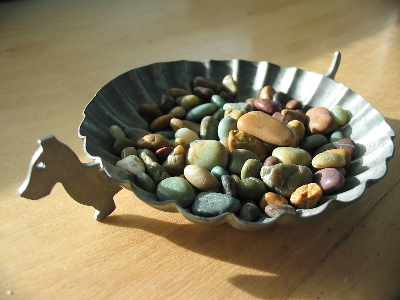 Some little smooth stones in an old ashtray.
