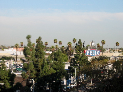 A sign for a car dealership, among some trees and buildings.