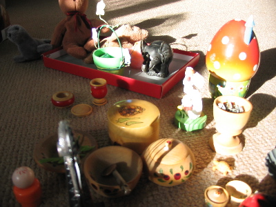 A bunch of small objects on the floor of my room: boxes, dolls, wooden cups, etc.